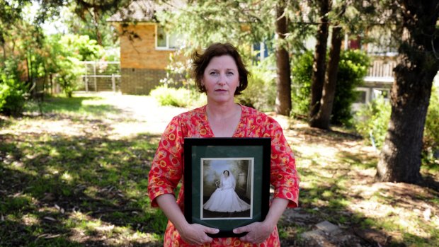Robyn Elliott with a photo of her mother Geraldine Elliott, outside her former home in Hughes.