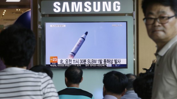 People watch a TV news program showing file footage of North Korea's ballistic missile that the North claimed to have launched from underwater, at Seoul Railway station in Seoul.