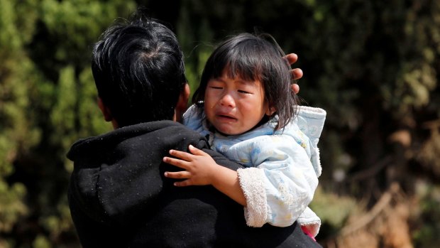A girl cries on her father's shoulder as they wait to be evacuated by a volunteer rescue team after fighting broke out in Laukkai.