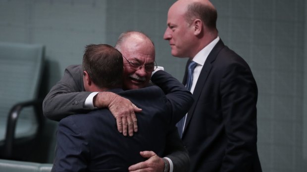 Government gay marriage supporters Tim Wilson and Warren Entsch embrace as Trent Zimmerman watches on.