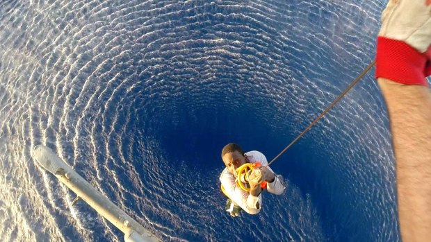 A migrant is lifted on board the Italian Navy ship Orione, after he and another migrant were spotted clinging to a barrel in the Mediterranean Sea, between Libya and Italy.