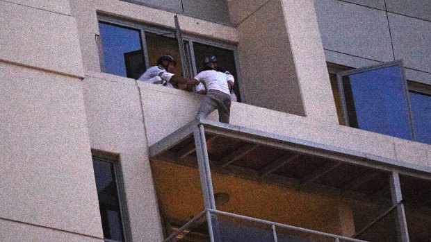 June Oh Seo, who spent the day on an awning on a high-rise building in Chatswood, gives himself up to Police Rescue members. 