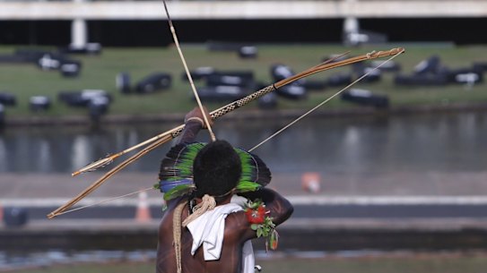 An indigenous man aims his arrow at police during a protest outside the National Congress in Brasilia, Brazil, on Tuesday.