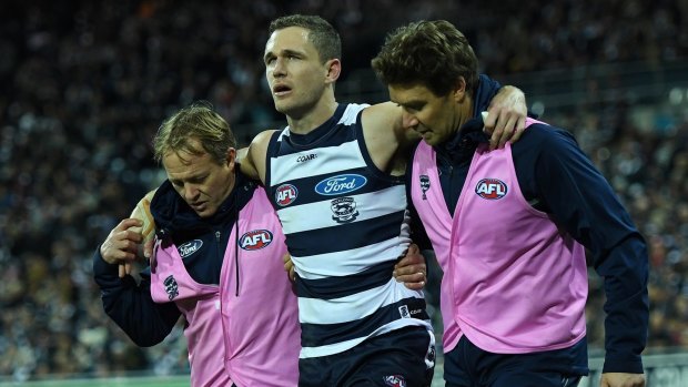 Joel Selwood hobbles around the boundary after hurting his ankle against the Swans