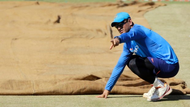 Indian cricketer Mahendra Singh Dhoni inspects the pitch.