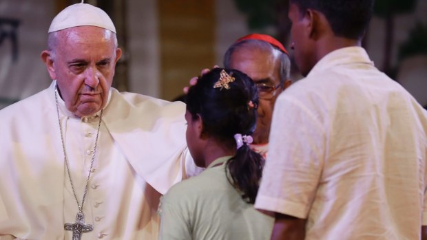 Pope Francis touches the head of a Rohingya Muslims refugee during an interfaith and ecumenical meeting for peace in the garden of the archbishop's residence, in Dhaka, Bangladesh.