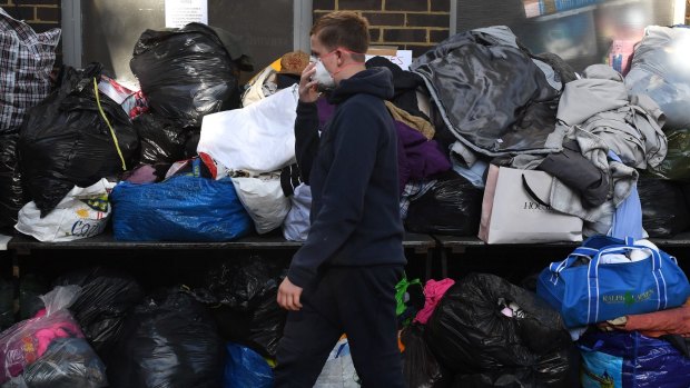 A boy wears a face mask as he walks past clothing, water and food that has been provided at Latymer Church near to the 24 storey residential Grenfell Tower block in Latimer Road.