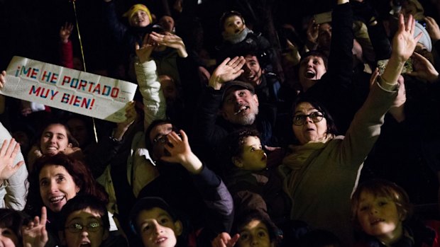 People wave and ask for candy while some holding banners reading "My behaviour has been very good" during the Three Wise Men parade in Madrid.