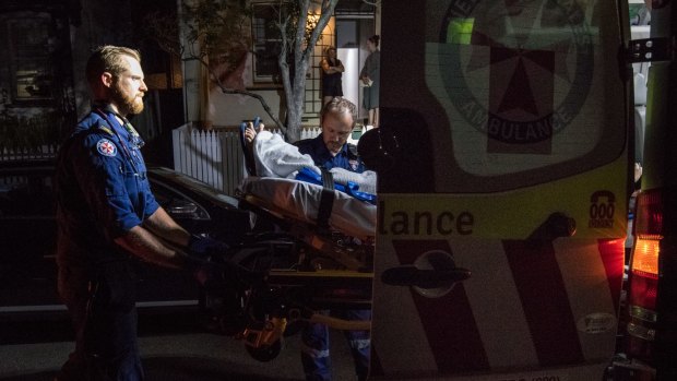 Paramedic Gareth Garne (left) loads the Leichhardt man into an ambulance.