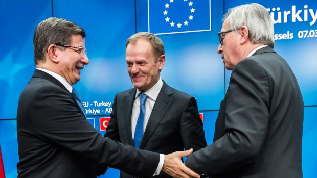 Turkish Prime Minister Ahmet Davutoglu, left, shakes hands with European Commission President Jean-Claude Juncker, right, and European Council President Donald Tusk, centre, after a final media conference at an EU summit in Brussels on Tuesday.