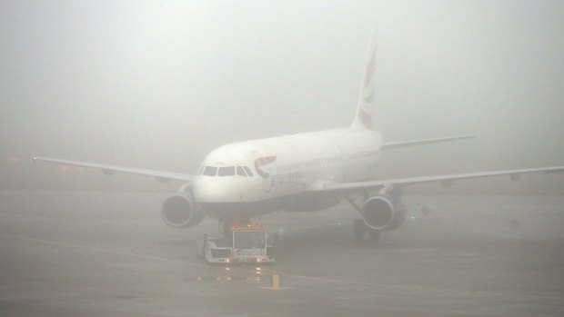 A British Airways plane seen through fog at Heathrow Airport, London, as thick fog disrupts flights at many UK airports for a second day on Monday.