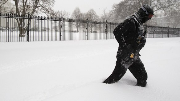 A uniformed US Secret Service police officer stands guard in a knee-deep snow outside the White House in Washington.