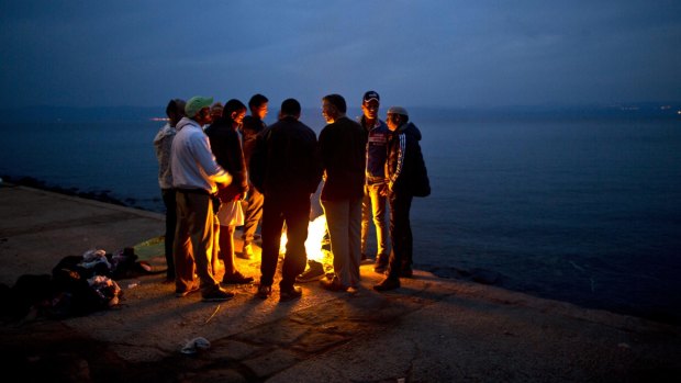 Afghan refugees gather around a fire to warm themselves after arriving on Lesbos.