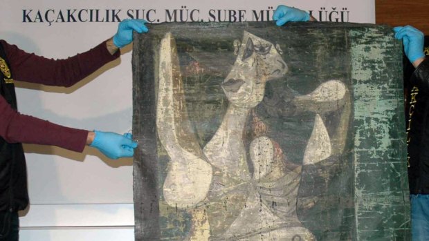 Turkish police officers hold the recovered oil painting.