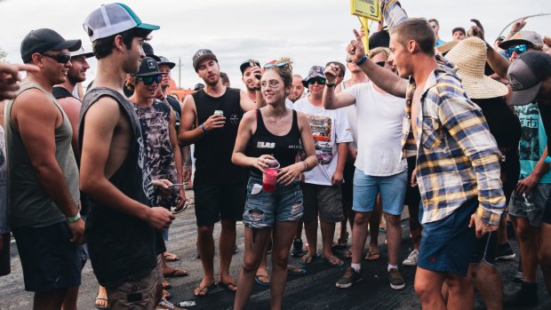 A group of men surround a young woman and shout 'black top, black top' requesting she remove her top. She didn't remove her top.