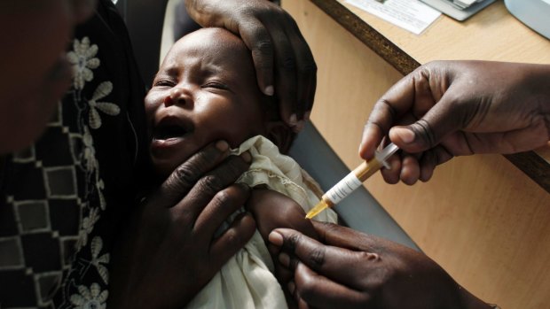 A mother holds her baby as she receives the candidate vaccine as part of a trial in western Kenya. 