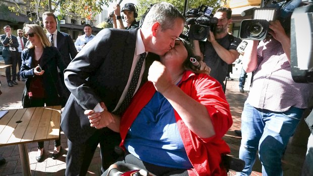 Opposition Leader Bill Shorten gets pulled in for a kiss by Margo during a street walk in Adelaide on Tuesday.