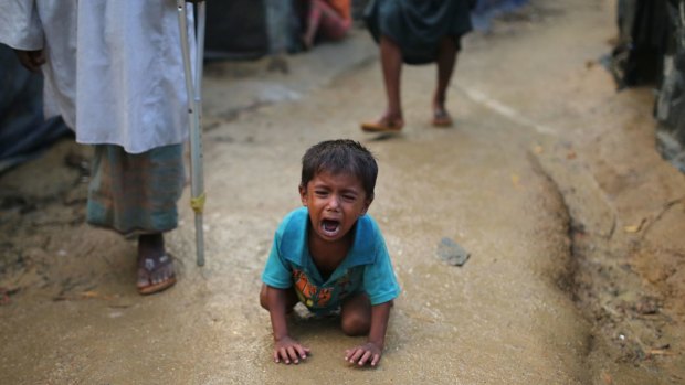 A Rohingya child cries kneeling on the ground at a makeshift camp near Kutupalong refugee camp in Cox's Bazar, Bangladesh.
