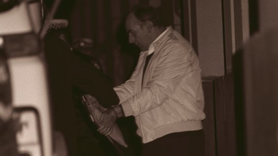 Stan Taylor, handcuffed, leaves the Supreme Court escorted by police