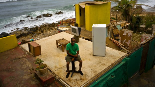 Roberto Figueroa Caballero sitting on a small table in his home that was destroyed by Hurricane Maria in La Perla suburb on the coast of San Juan, Puerto Rico.
