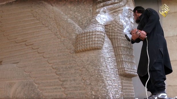 An Islamic State militant destroys the statue of Lamassu, an Assyrian deity, with a jackhammer in the northern Iraqi Governorate of Nineveh.
