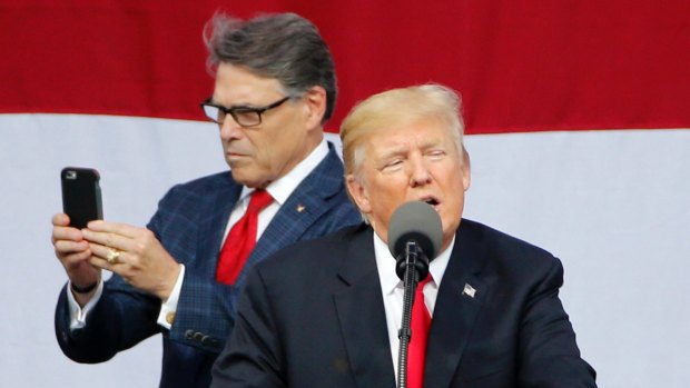 Perry uses his phone while Trump delivered a speech on Monday.