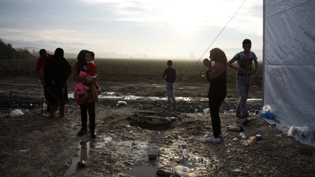 People sit outside tents as they wait to be allowed to cross from the northern Greek village of Idomeni to southern Macedonia.