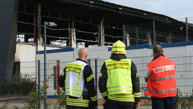 Emergency services workers outside a sports hall in Nauen on Tuesday. Intended to house refugees and migrants applying for asylum in Germany, the hall was burned.