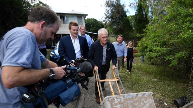 Australian Prime Minister Malcolm Turnbull helps residents with clean-up as he tours a flood-damaged street in Eagleby.