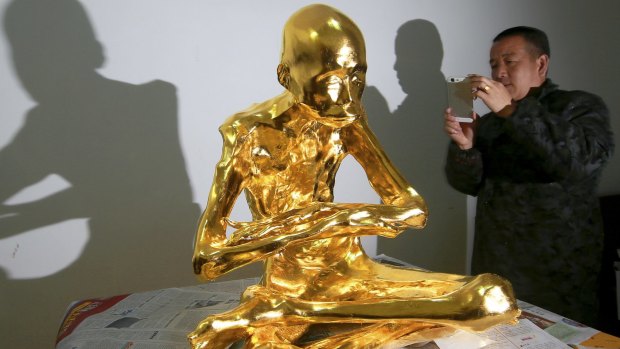 A man takes a photo of the mummified body of revered Buddhist monk Fu Hou in Quanzhou city in southeastern China's Fujian province. 