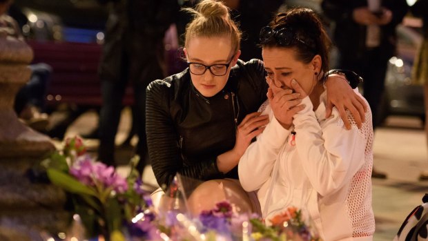 A woman is consoled as she looks at the floral tributes following an evening vigil outside the Town Hall in Manchester. 