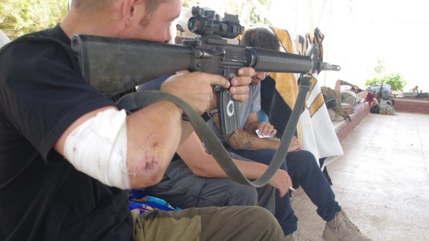 Siyar points an M-16 as another western volunteer sits between him and Rob, whose face is obscured by the barrel.