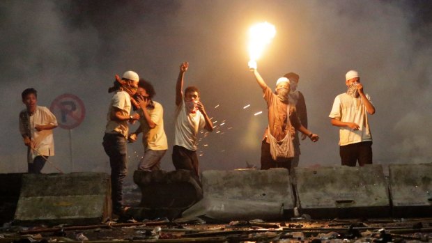 A protester holds up a blowtorch during a clash with police outside the presidential palace in Jakarta.