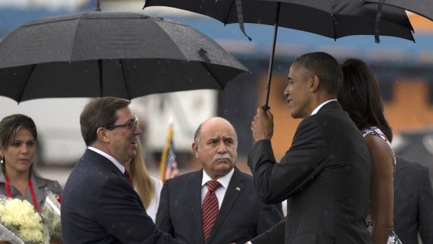 President Barack Obama, right, shakes hands with Cuba's Foreign Minister Bruno Rodriguez as first lady Michelle Obama stands behind, right, at the airport in Havana, Cuba.