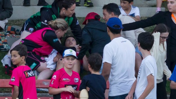 A boy is treated after being hit by a ball during the Women's Big Bash League cricket match between the Sydney Sixers and the Melbourne Stars at North Sydney Oval on Saturday. 
