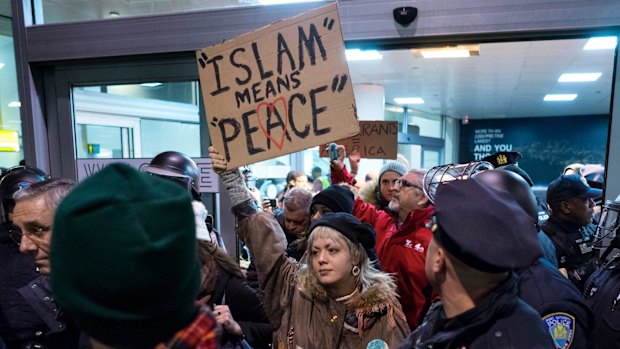 Protesters are surrounded by police officers and travelers as they pass through an exit of Terminal 4 at John F. Kennedy International Airport in New York.