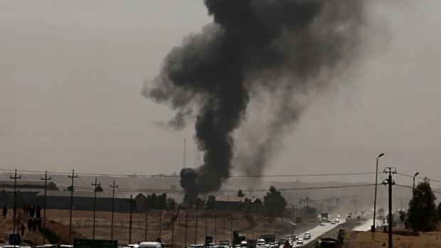 Smoke rises while Iraqi security forces use bombs as Kurdish security forces withdraw from a checkpoint in Alton Kupri, outskirts of Irbil, Iraq.