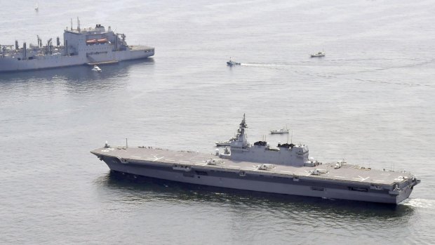 Japan's helicopter carrier Izumo, foreground, sails by a US supply ship, top left.