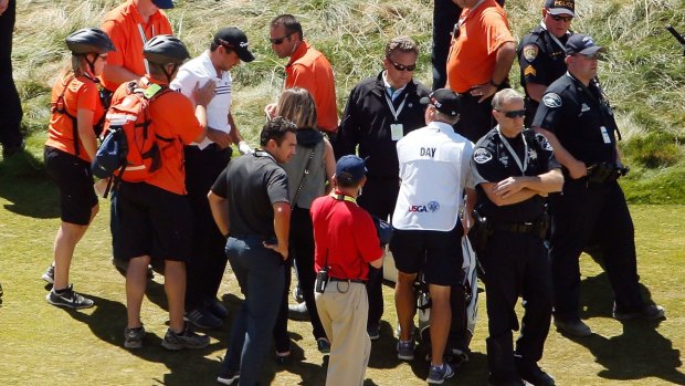 Jason Day is helped to his feet by medics.