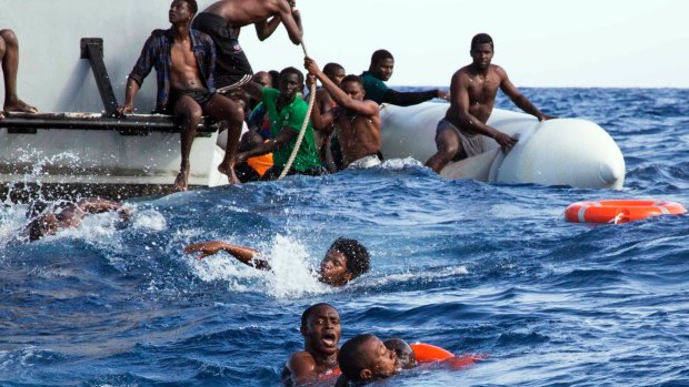 Migrants from a sinking inflatable dinghy try to board a Libyan coast guard ship during a rescue operation earlier this month.