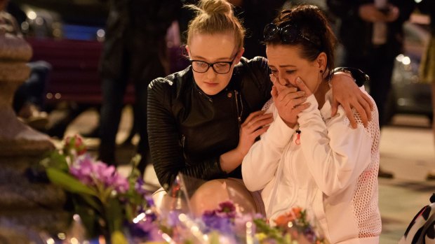A woman is consoled as she looks at the floral tributes following an evening vigil outside the Town Hall in Manchester. 