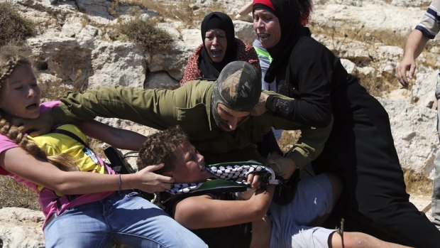 Palestinian women and youth scuffle with an Israeli soldier trying to arrest a 12-year-old boy during a protest near the West Bank village of Nebi Saleh. 