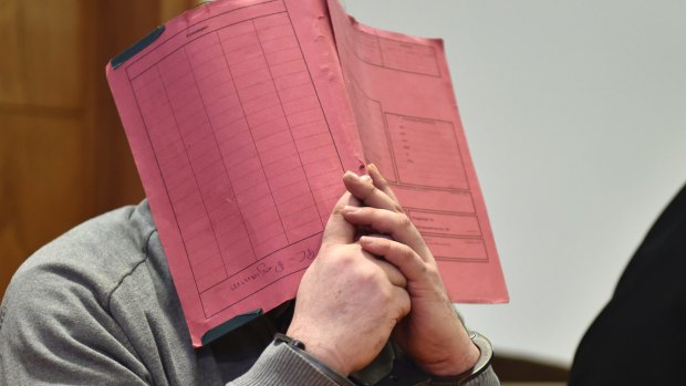 Former nurse Niels Hoegel, accused of multiple murder and attempted murder of patients, covering his face with a file at the district court in Oldenburg, Germany in February.