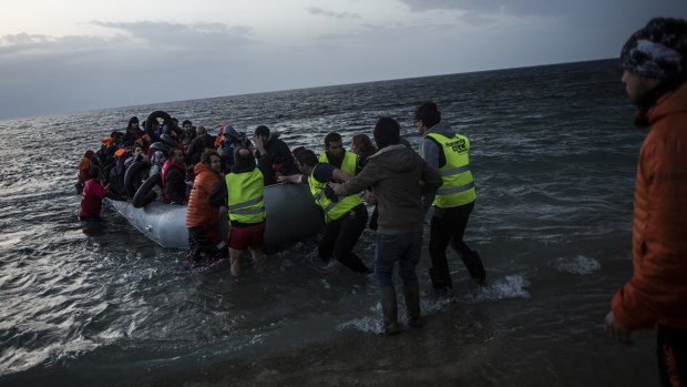 Volunteers assist refugees and migrants on a beach in Lesbos after crossing the Aegean sea.