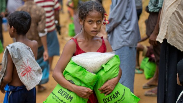 A newly arrived Rohingya girl carries bags of food rations in Kutupalong, Bangladesh.