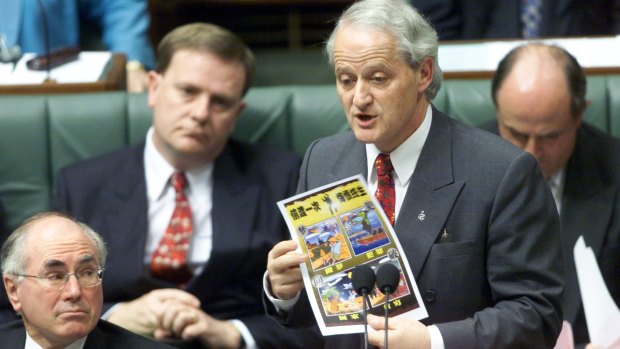 Philip Ruddock  speaks about illegal boat people in Parliament, while  holding a poster on the subject.