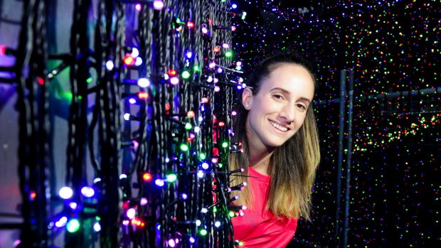 Gabrielle Weider from Sids and Kids surrounded by Christmas lights.