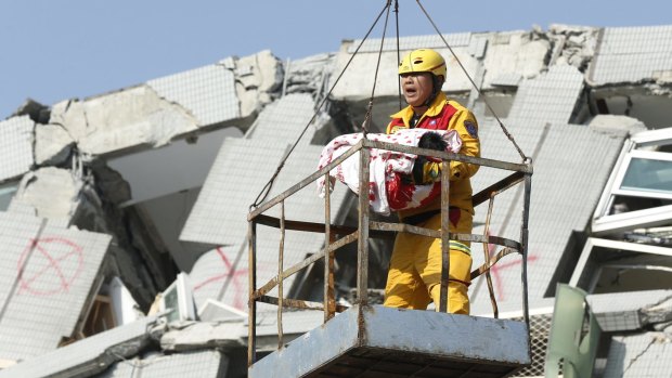 An emergency worker carries a rescued six-month-old baby girl from the rubble of a collapsed building in Tainan, Taiwan, on Sunday.