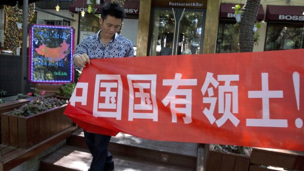 A worker at a restaurant bar puts up a banner which partly reads: "South China Sea is China's territory" in Beijing on Wednesday.