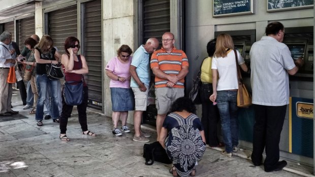 Athenians queue up to withdraw money from an ATM. The Greek government has imposed a €60 daily limit.
